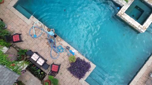 Aerial view of backyard pool being cleaned